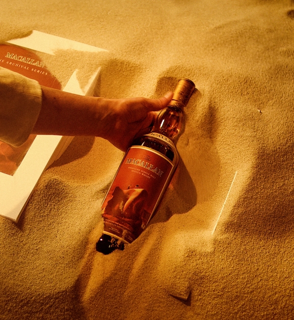 The Macallan Folio 8 bottle pack and hand in sand