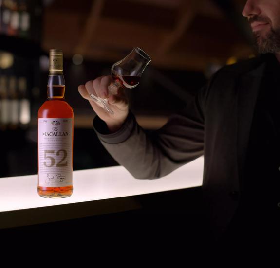 the macallan 52 years old 2018 release whisky bottle and man holding dram