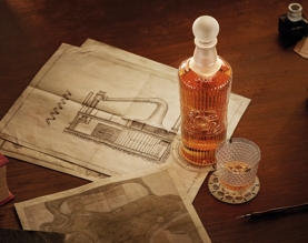 tales of the macallan bottle and glass on table with still drawing