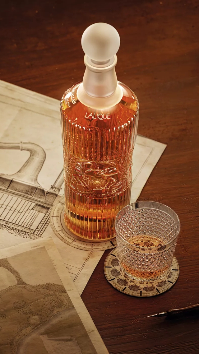 tales of the macallan bottle and glass on table with still drawing