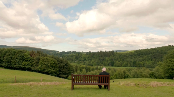 Sir Peter Blake sitting on bench