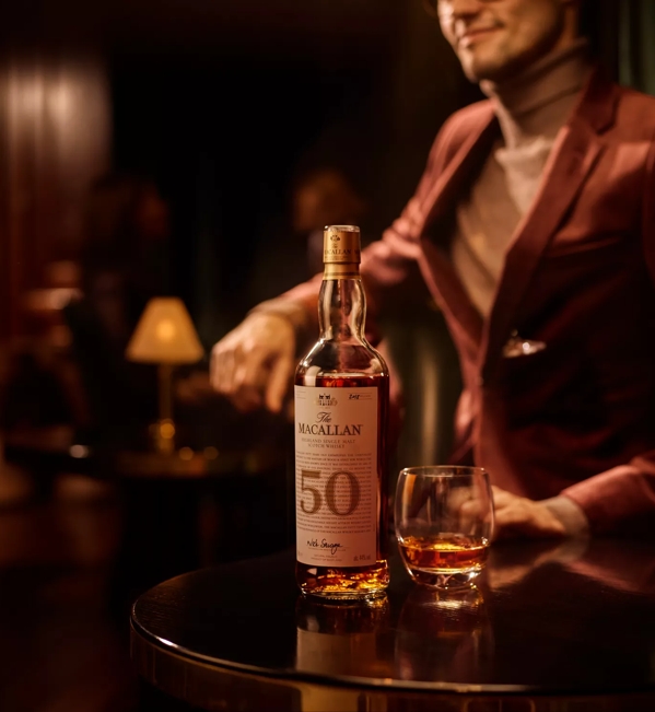 man with the macallan 50 years old 2018 release whisky bottle and glass in bar setting
