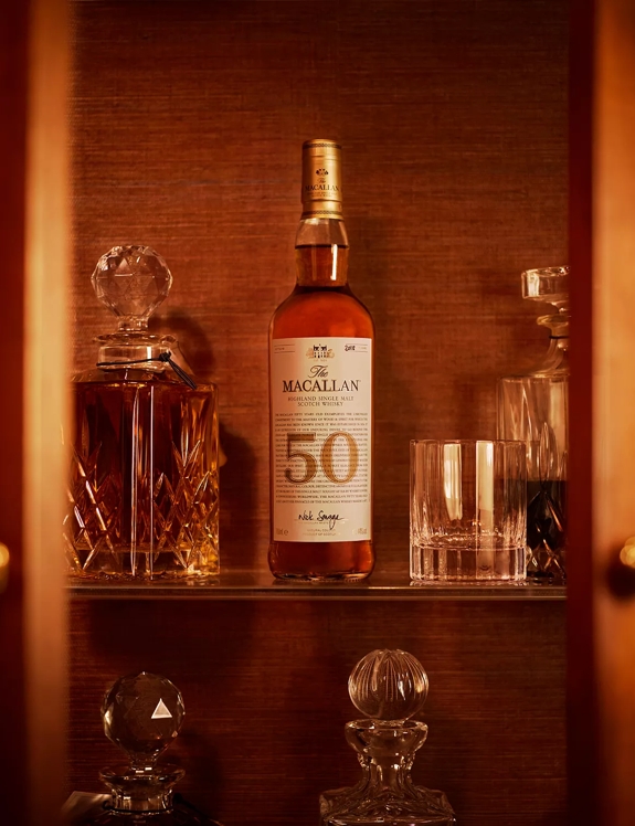 the macallan 50 years old 2018 release whisky bottle sitting on bar shelf with glasses