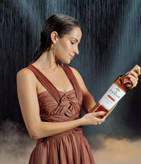 The Macallan Classic Cut 2023 Release Model Looking Down at Classic Cut Bottle with Rain in Background