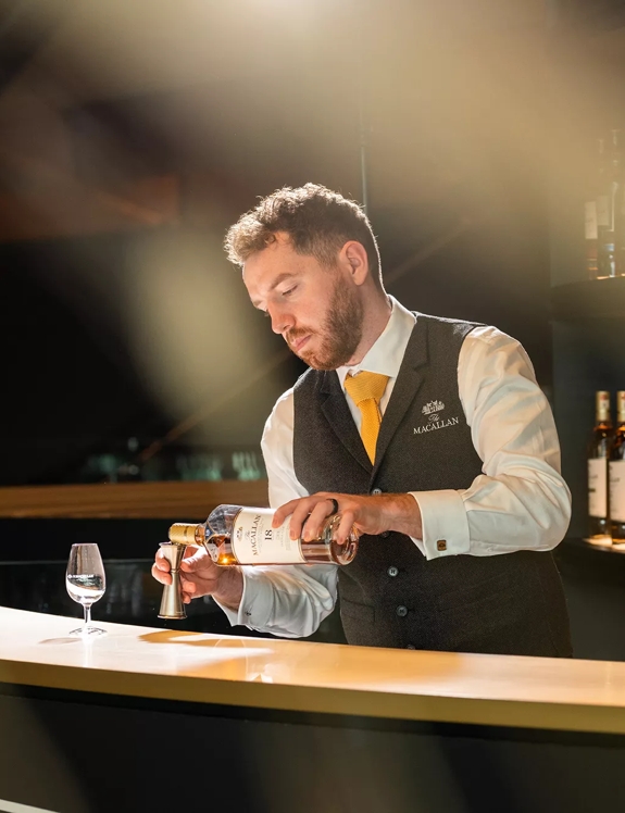Man pouring drams behind The Macallan Distillery Bar