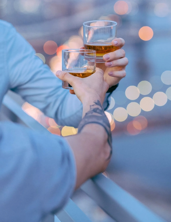 two hands holding whisky glasses in air