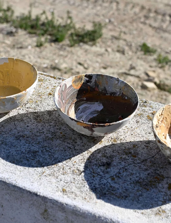 artists paint bowls in the sun